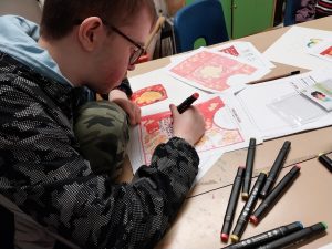 Student drawing and colouring ACE packaging