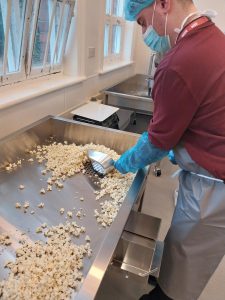 Marketing Apprentice scooping popcorn over holes in tray