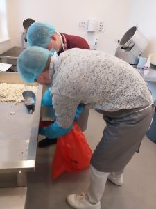 Social Enterprise Lead holding bag while Marketing Apprentice scoops popcorn into bag