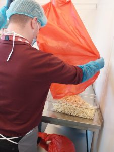 Marketing Apprentice pouring popcorn from red bag into transparent tray