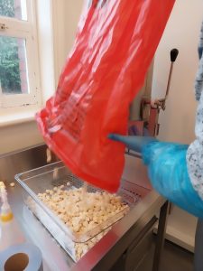 Popcorn being poured from red bag into transparent tray