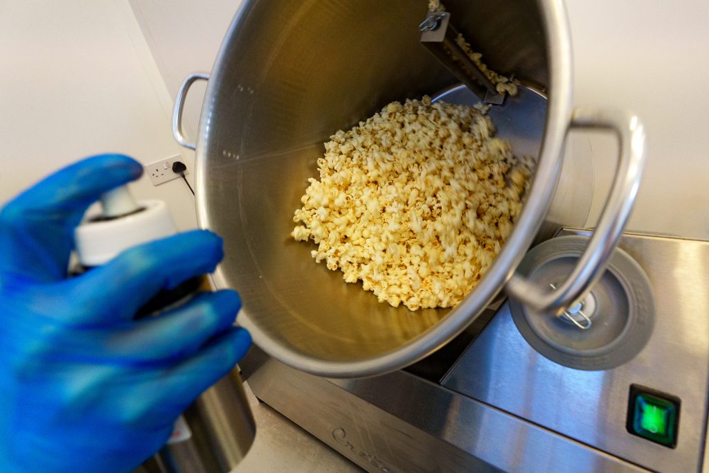 Production Assistant spraying popcorn in mixer